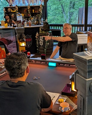 Tim at the table, laughing mid-scene, hands raised as if calling out a player in a moment for something funny.